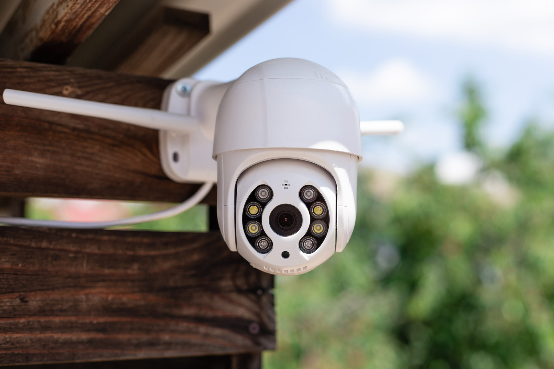 white security camera mounted to fence boards