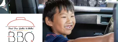 Kid sitting in the driver's seat of a police vehicle smiling